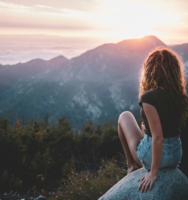 woman looking at the sunset over a mountain | financialtherapysolutions.com