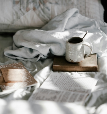 a mug and a book on a bed | financialtherapysolutions.com