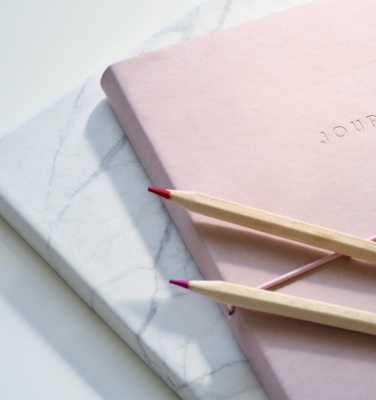 pink journal and colored pencils | financialtherapysolutions.com