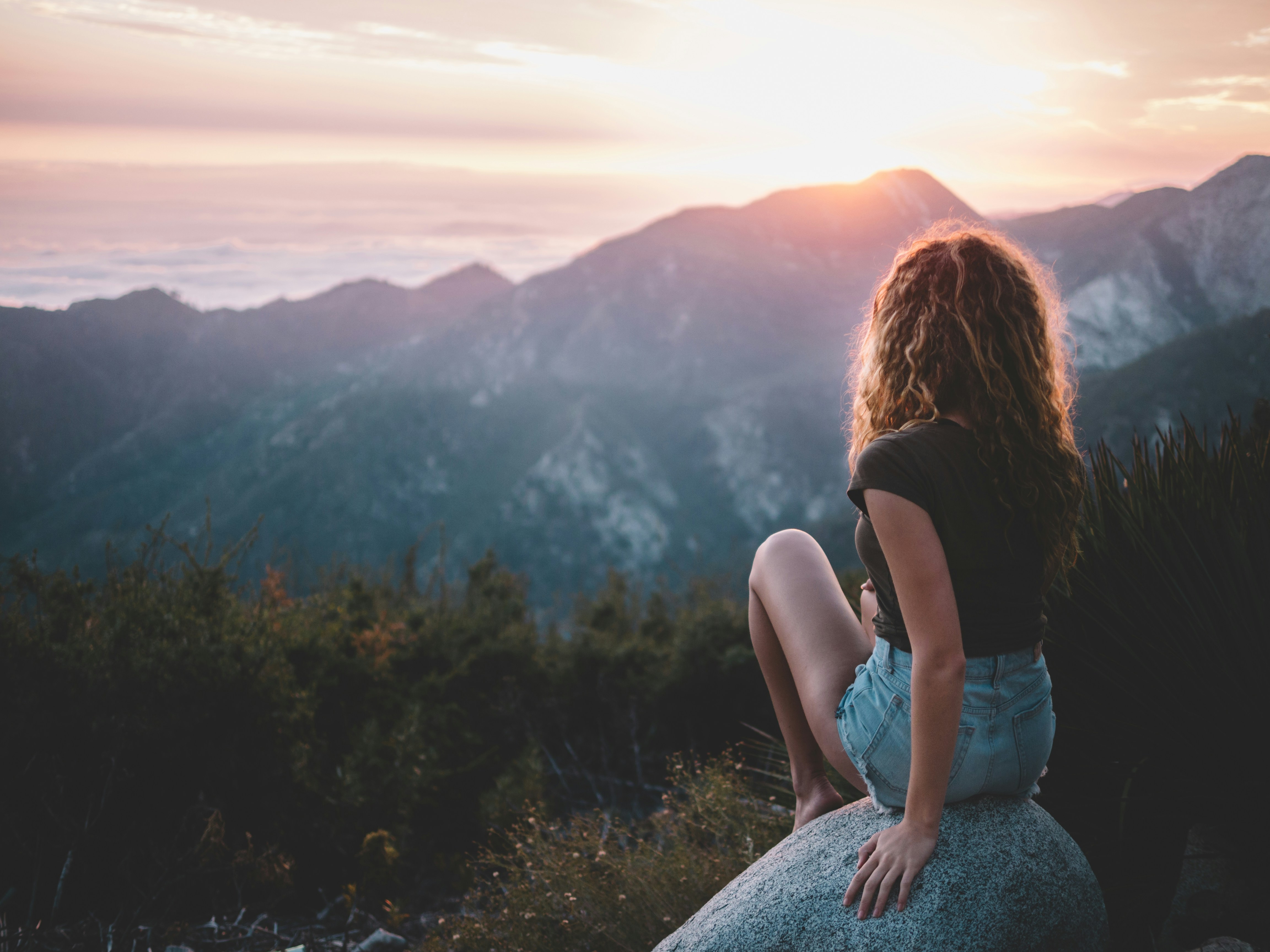 woman looking at the sunset over a mountain | financialtherapysolutions.com